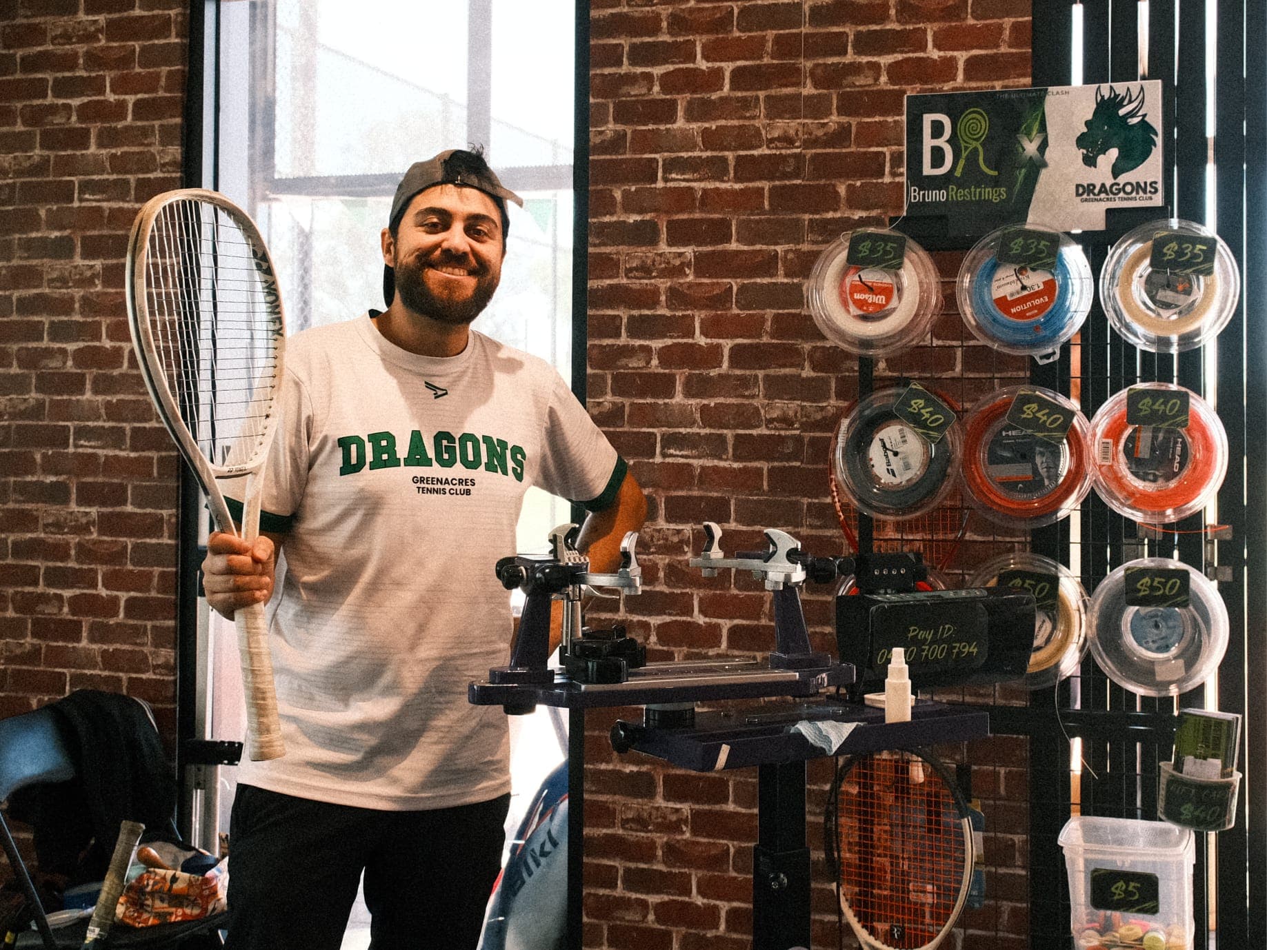 Bruno at his stringing machine next to the string wall, reels priced $35, $40 and $50